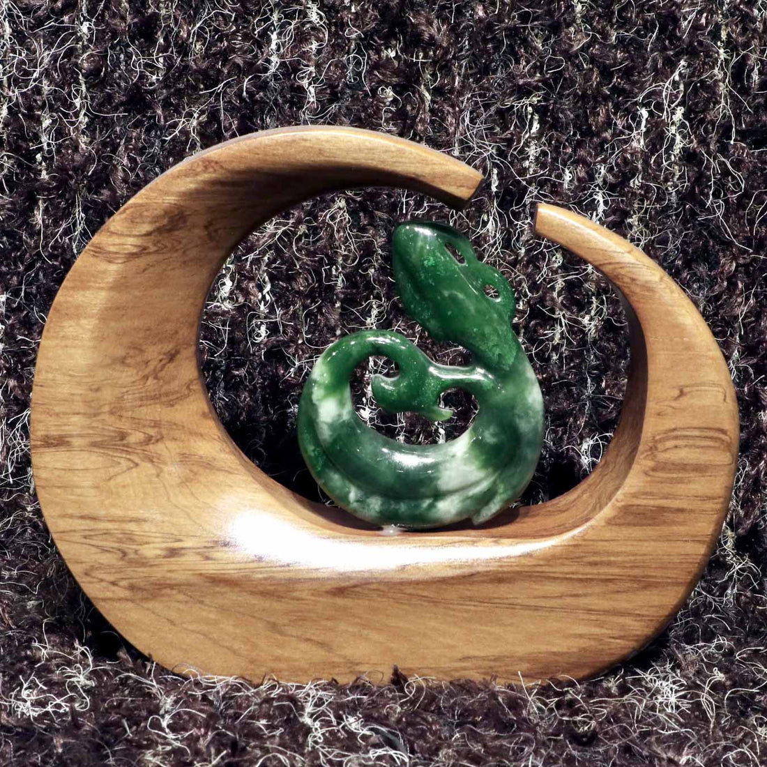 carved jade manaia on a kauri stand