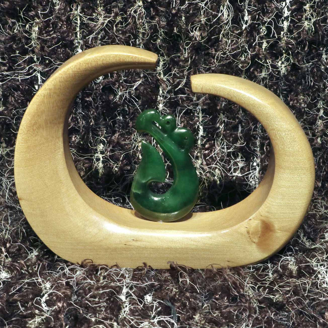 carved jade manaia mounted on a kauri stand