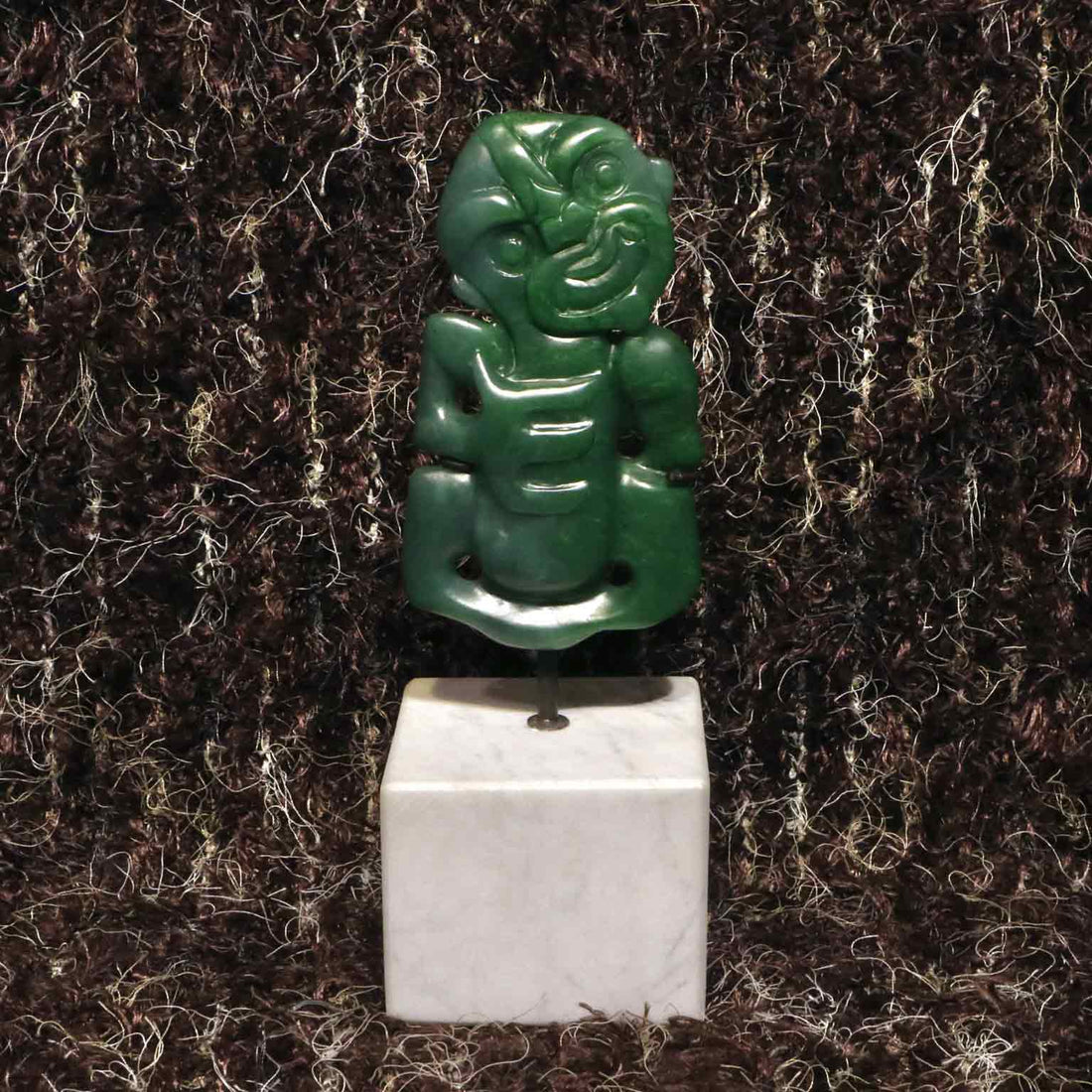 carved jade tiki mounted on a stand
